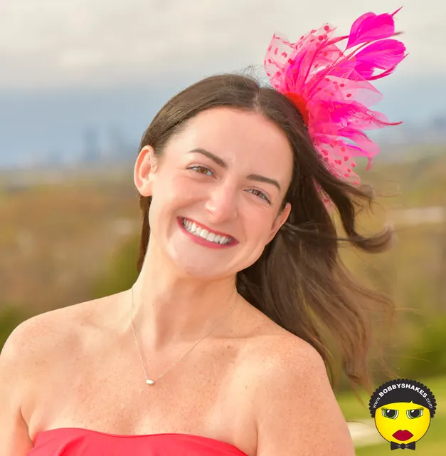 Smiling guest with a pink feather fascinator